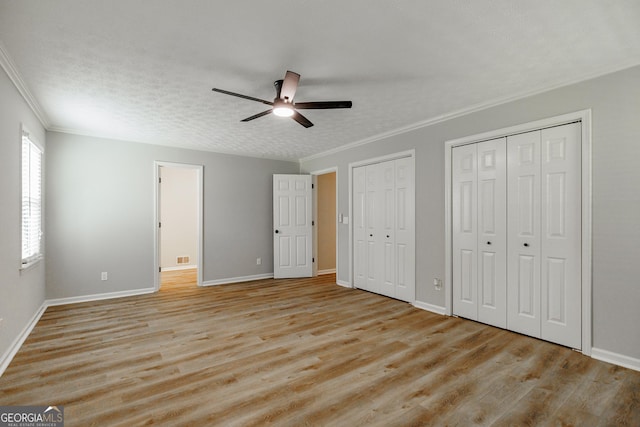 870 Rutherford Dr, Dacula, GA 30019 - unfurnished bedroom featuring crown molding, light wood finished floors, two closets, and ceiling fan