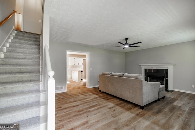 870 Rutherford Dr, Dacula, GA 30019 - living room featuring wood finished floors, a ceiling fan, stairs, a fireplace, and a textured ceiling