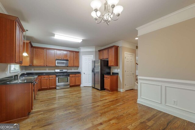 2264 Ewell Park Dr, Lawrenceville, GA 30043 - kitchen with stainless steel appliances, dark countertops, light wood-style floors, brown cabinets, and ornamental molding