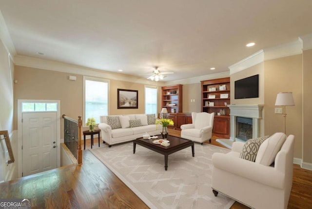2264 Ewell Park Dr, Lawrenceville, GA 30043 - living area with wood finished floors, crown molding, a fireplace with raised hearth, a ceiling fan, and recessed lighting