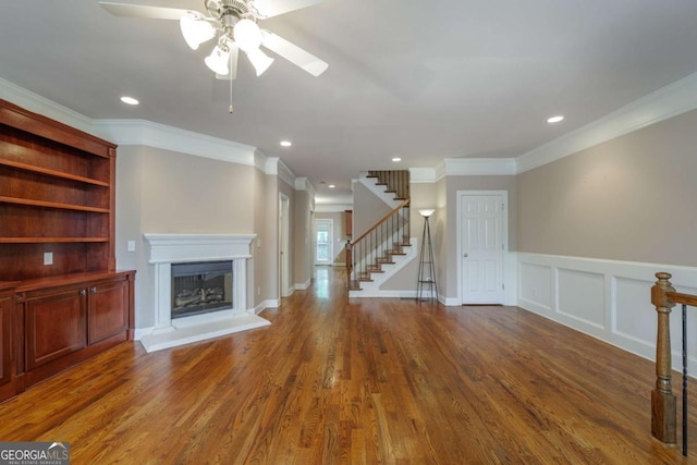 2264 Ewell Park Dr, Lawrenceville, GA 30043 - unfurnished living room featuring a ceiling fan, stairway, a fireplace with raised hearth, ornamental molding, and wood finished floors