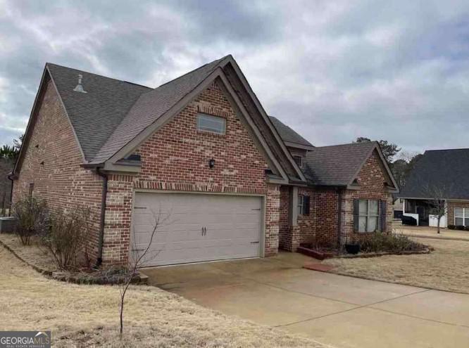3349 Alhambra Cir, Hampton, GA 30228 - view of front of home with brick siding, concrete driveway, roof with shingles, and a garage
