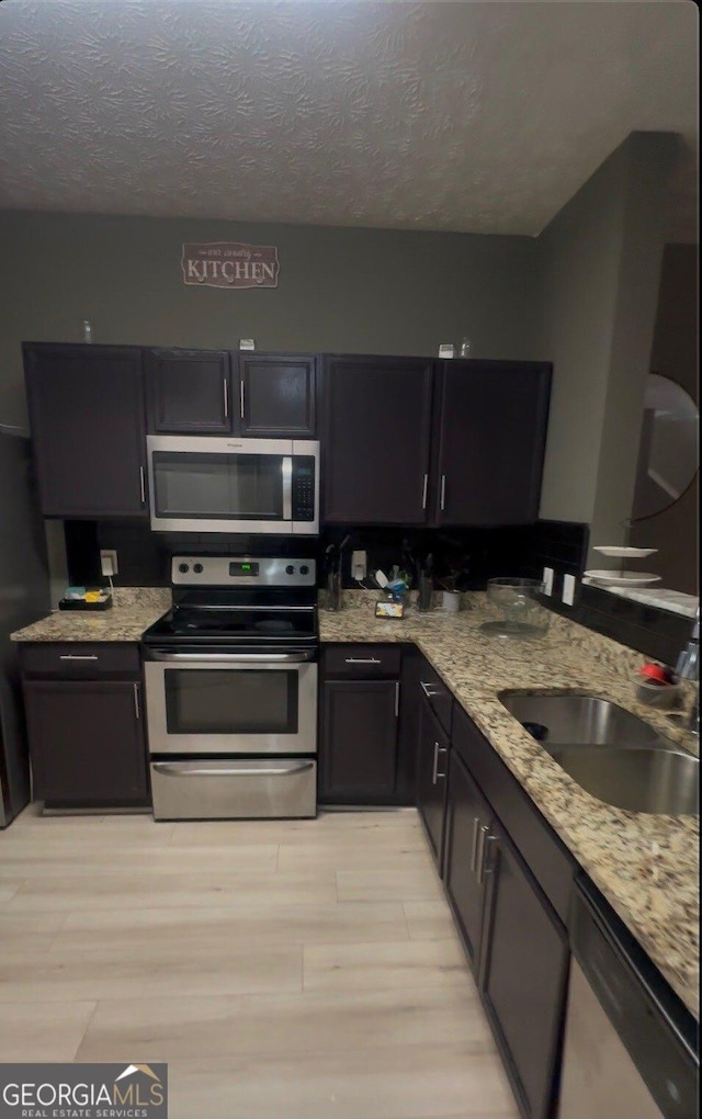 1794 Fielding Way, Hampton, GA 30228 - kitchen featuring appliances with stainless steel finishes, light wood finished floors, light stone countertops, and a textured ceiling