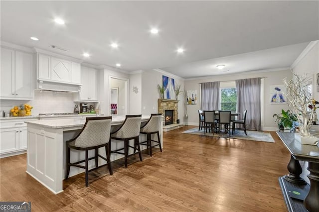 10 Nesbit Reserve Ct, Atlanta, GA 30350 - kitchen with crown molding, white cabinetry, tasteful backsplash, a center island with sink, and a breakfast bar
