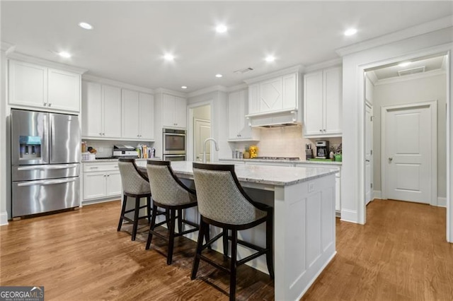 10 Nesbit Reserve Ct, Atlanta, GA 30350 - kitchen with stainless steel appliances, a kitchen island with sink, a breakfast bar area, tasteful backsplash, and crown molding