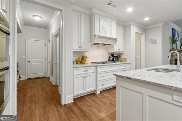 10 Nesbit Reserve Ct, Atlanta, GA 30350 - kitchen with crown molding, wood finished floors, stainless steel gas cooktop, backsplash, and white cabinetry