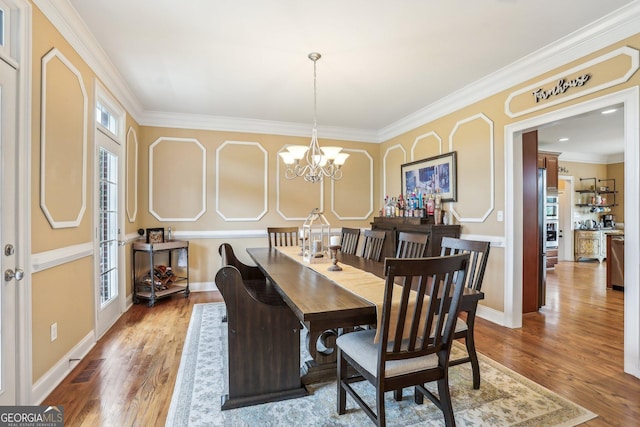 3480 Indian Shoals Rd, Dacula, GA 30019 - dining room featuring wood finished floors, ornamental molding, and a chandelier