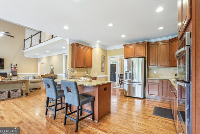 3480 Indian Shoals Rd, Dacula, GA 30019 - kitchen featuring appliances with stainless steel finishes, a peninsula, ornamental molding, open floor plan, and light wood-style flooring