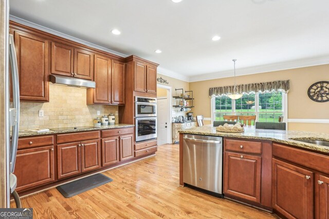 3480 Indian Shoals Rd, Dacula, GA 30019 - kitchen featuring stainless steel appliances, under cabinet range hood, ornamental molding, backsplash, and light wood finished floors
