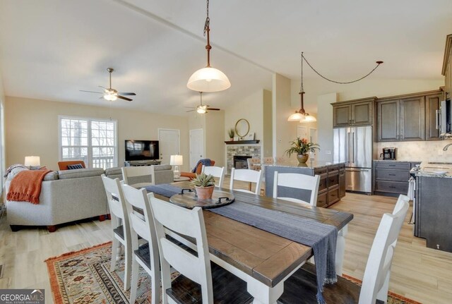 243 Degroff Ln, Rabun Gap, GA 30568 - dining room with vaulted ceiling, a ceiling fan, light wood finished floors, and a fireplace