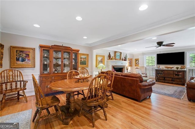 226 Nacoochee Dr, Woodstock, GA 30188 - dining room featuring crown molding, light wood-type flooring, a fireplace, a wainscoted wall, and a ceiling fan