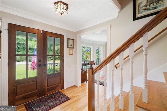 226 Nacoochee Dr, Woodstock, GA 30188 - entryway with french doors, light wood-type flooring, ornamental molding, wainscoting, and stairway