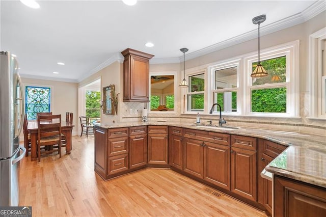 226 Nacoochee Dr, Woodstock, GA 30188 - kitchen with freestanding refrigerator, brown cabinetry, light wood-style floors, light stone countertops, and crown molding