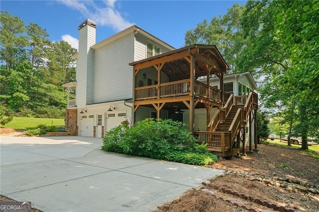 226 Nacoochee Dr, Woodstock, GA 30188 - back of property with a chimney, an attached garage, stairs, concrete driveway, and a wooden deck