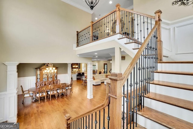 2450 Weber Heights Way, Buford, GA 30519 - stairs with decorative columns, wood finished floors, crown molding, a chandelier, and a decorative wall