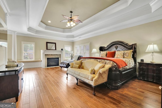 2450 Weber Heights Way, Buford, GA 30519 - bedroom with a raised ceiling, hardwood / wood-style flooring, crown molding, decorative columns, and a fireplace with flush hearth