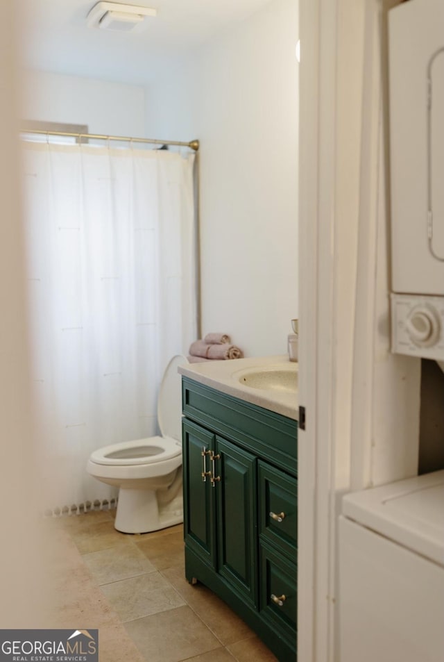 351 Cherokee Ave SE Apt 10, Atlanta, GA 30312 - bathroom featuring estacked washer and dryer, vanity, toilet, a shower with curtain, and tile patterned flooring