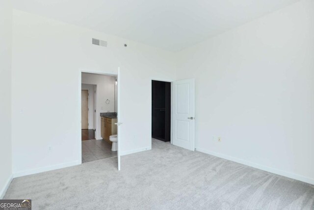 361 17th St NW Unit 1702, Atlanta, GA 30363 - unfurnished bedroom featuring light carpet, baseboards, and connected bathroom