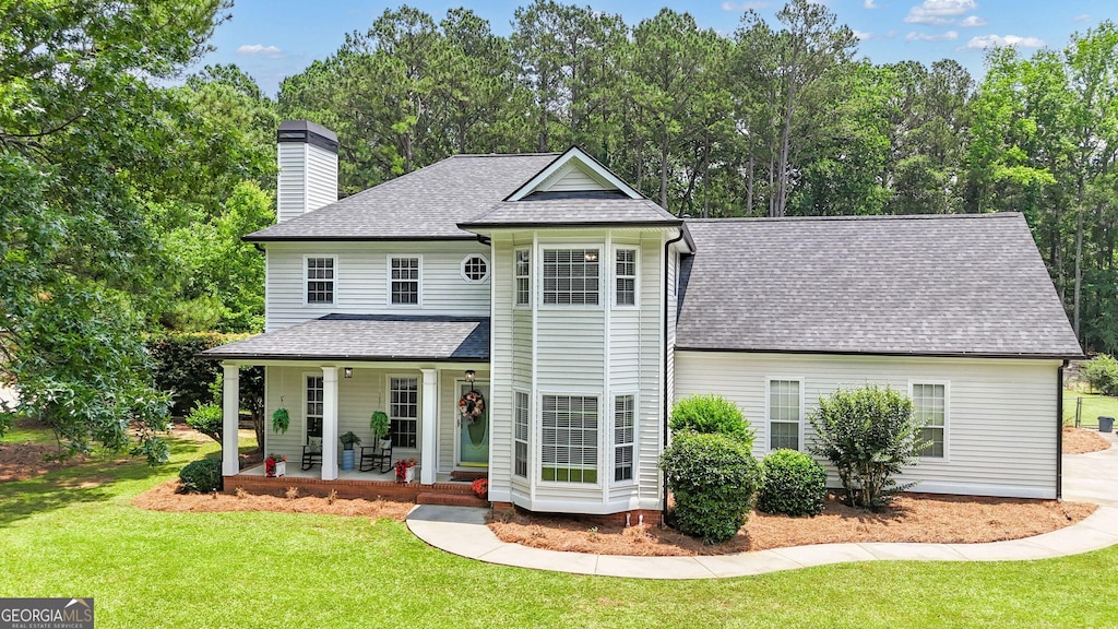 140 Laurel Lake Rd, Tyrone, GA 30290 - view of front facade featuring a porch, a front yard, a chimney, a shingled roof, and view of scattered trees