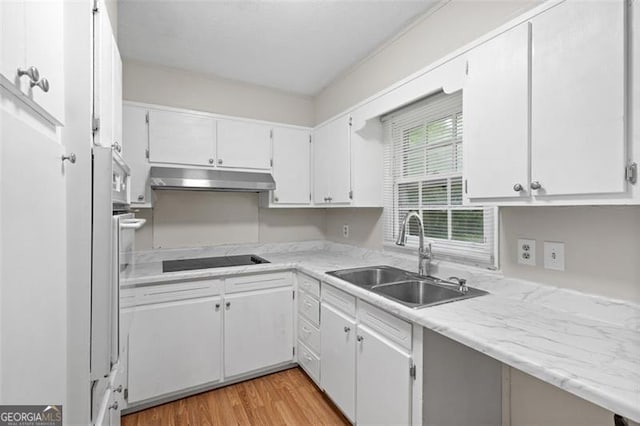 1594 Pine Glen Cir, Decatur, GA 30035 - kitchen with under cabinet range hood, black electric stovetop, light wood finished floors, and white cabinets