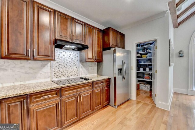 3085 Saint Andrews Dr, Duluth, GA 30096 - kitchen with stainless steel fridge, under cabinet range hood, black electric cooktop, light wood-style floors, and tasteful backsplash