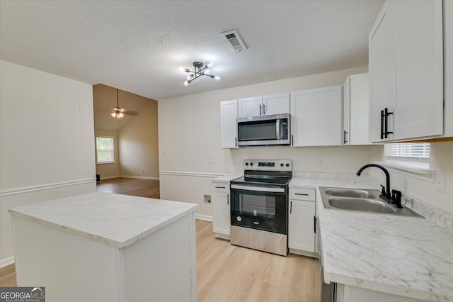 2011 Mims Rd, Hephzibah, GA 30815 - kitchen featuring stainless steel appliances, light wood-style flooring, healthy amount of natural light, white cabinets, and a textured ceiling