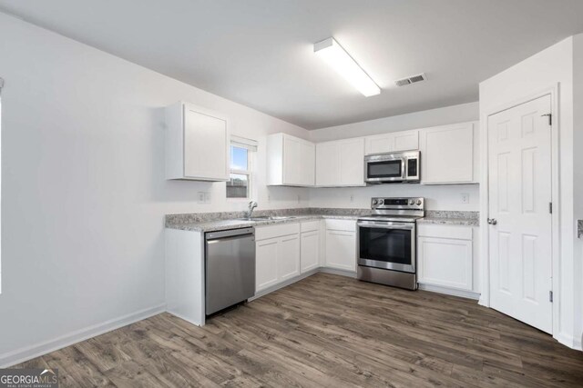 761 Riverside Dr NW, Calhoun, GA 30701 - kitchen with stainless steel appliances, white cabinetry, dark wood-style floors, and light countertops