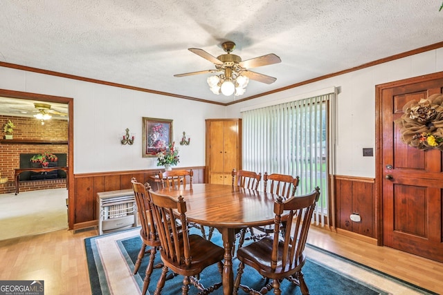 289 Hilton St, Monticello, GA 31064 - dining room with ceiling fan, light wood-style flooring, wood walls, a textured ceiling, and a wainscoted wall
