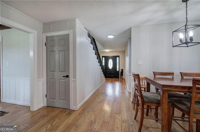 141 Holcomb Spur NW, Adairsville, GA 30103 - dining room with light wood finished floors, a decorative wall, a chandelier, stairs, and a textured ceiling