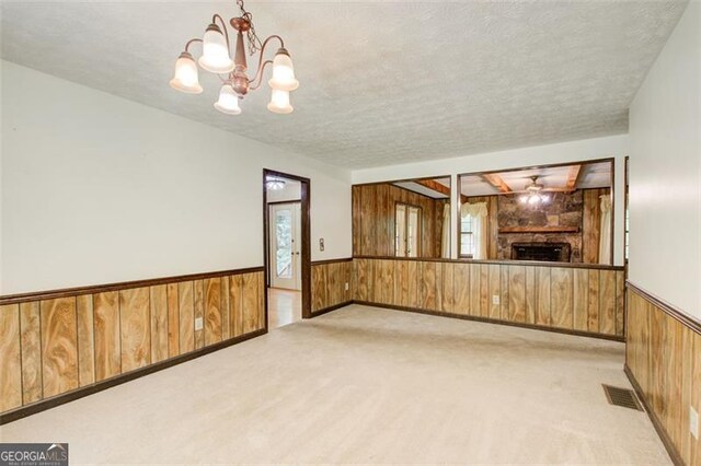 2612 Spring St, Dacula, GA 30019 - unfurnished living room featuring wooden walls, a wainscoted wall, light colored carpet, a chandelier, and a fireplace