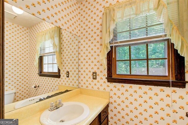 2612 Spring St, Dacula, GA 30019 - bathroom with wallpapered walls, vanity, and toilet