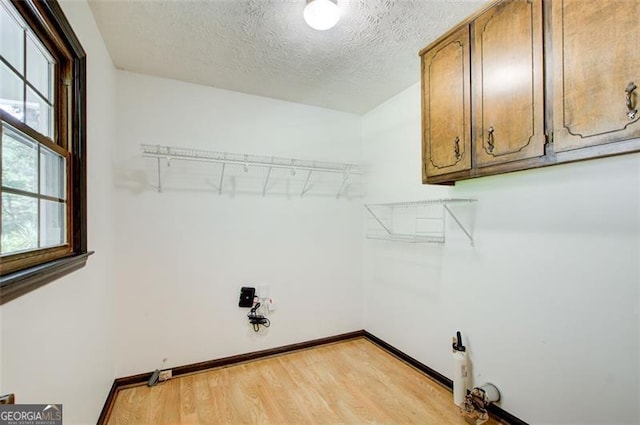 2612 Spring St, Dacula, GA 30019 - washroom featuring light wood-type flooring, a textured ceiling, baseboards, and cabinet space