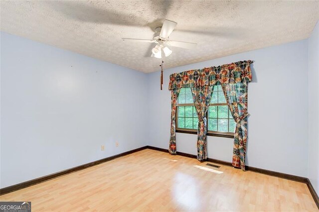 2612 Spring St, Dacula, GA 30019 - unfurnished room featuring wood finished floors, baseboards, a ceiling fan, and a textured ceiling