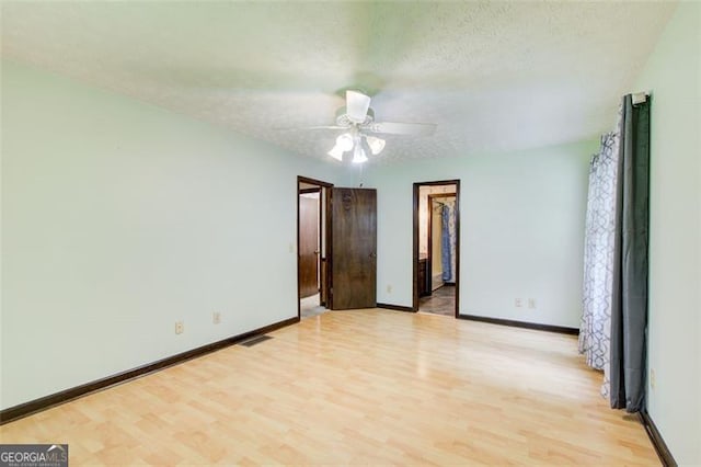 2612 Spring St, Dacula, GA 30019 - unfurnished bedroom with light wood finished floors, baseboards, a textured ceiling, a walk in closet, and a ceiling fan