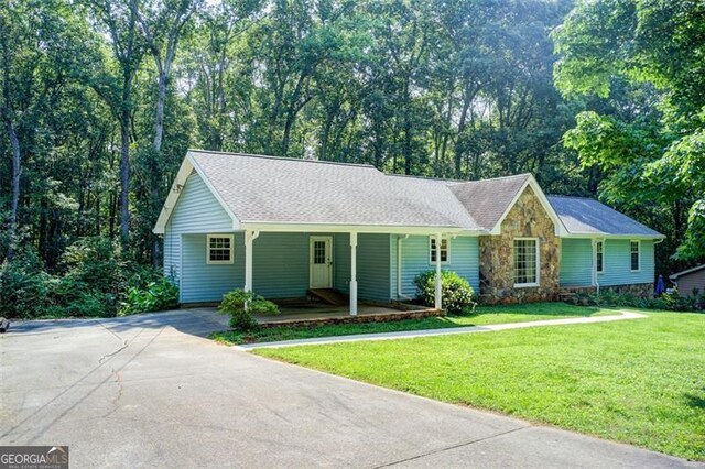 2612 Spring St, Dacula, GA 30019 - ranch-style house featuring asphalt driveway, a front lawn, stone siding, roof with shingles, and covered porch