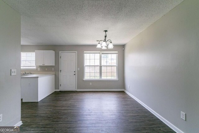 256 Turnstone Rd, Stockbridge, GA 30281 - unfurnished dining area featuring a chandelier, dark wood finished floors, and a textured ceiling