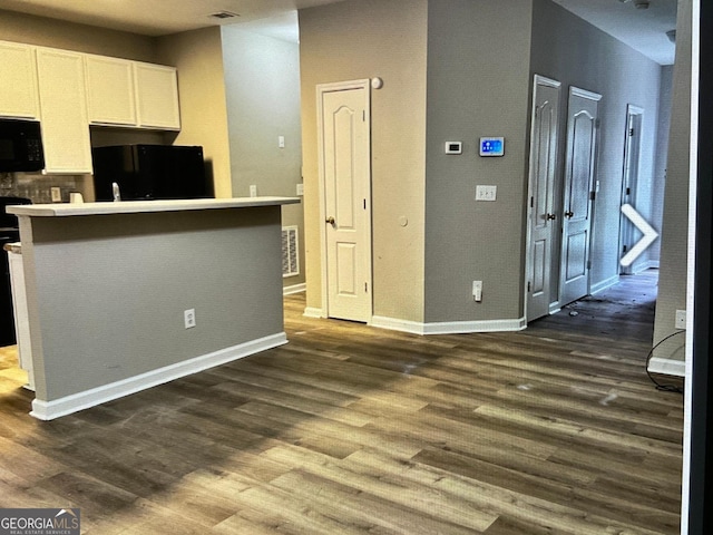 5057 Windsor Forrest Ln, Atlanta, GA 30349 - kitchen with black microwave, fridge, white cabinets, and dark wood finished floors