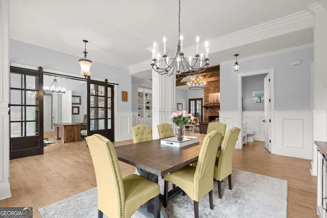13535 Blakmaral Ln, Milton, GA 30004 - dining space with a chandelier, light wood-type flooring, a decorative wall, wainscoting, and ornamental molding