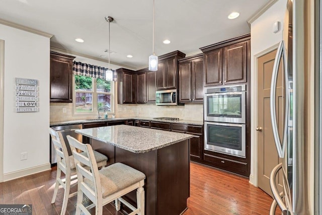 2525 Well Springs Dr, Buford, GA 30519 - kitchen featuring stainless steel appliances, dark brown cabinetry, light stone countertops, a center island, and a kitchen breakfast bar