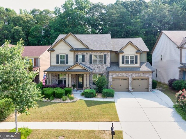 2525 Well Springs Dr, Buford, GA 30519 - craftsman house with driveway, an attached garage, covered porch, and brick siding