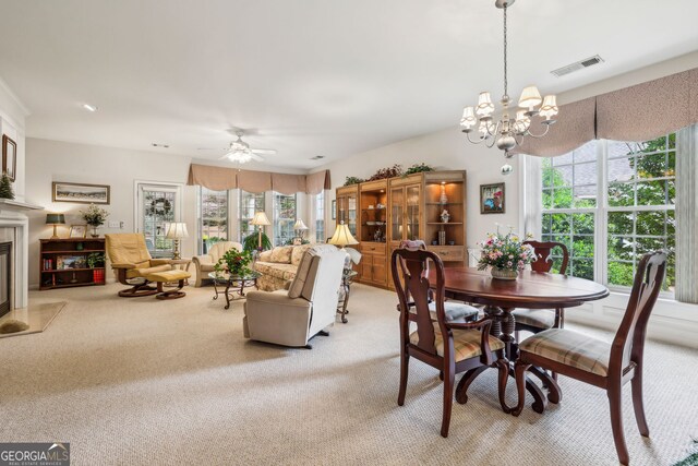 5105 Kings Common Way, Cumming, GA 30040 - dining area featuring light carpet, a ceiling fan, a chandelier, and a fireplace with flush hearth