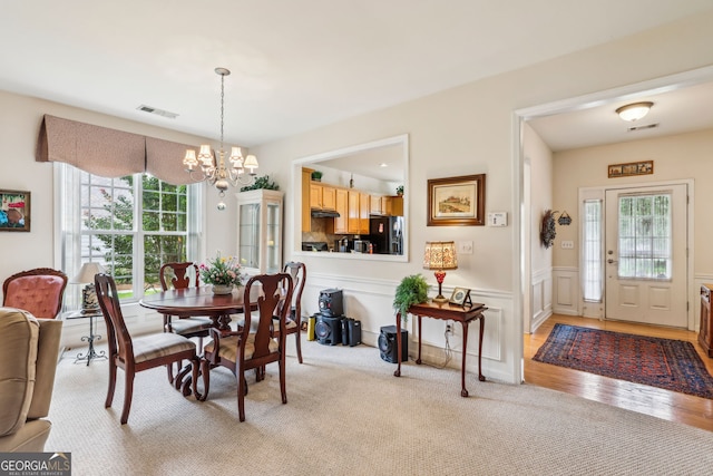 5105 Kings Common Way, Cumming, GA 30040 - dining space featuring a chandelier, wainscoting, light wood finished floors, and light colored carpet
