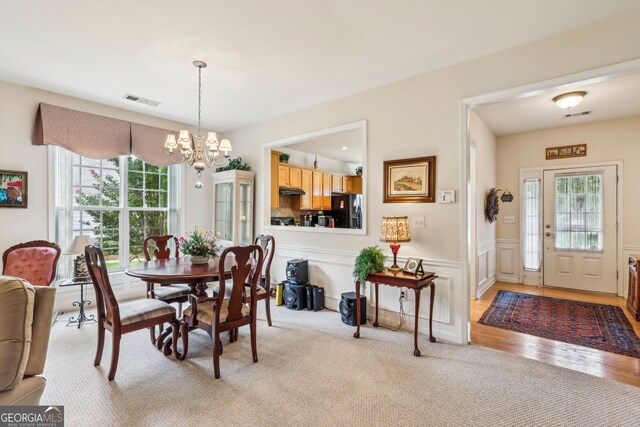 5105 Kings Common Way, Cumming, GA 30040 - dining space featuring a chandelier, wainscoting, light wood finished floors, and light colored carpet
