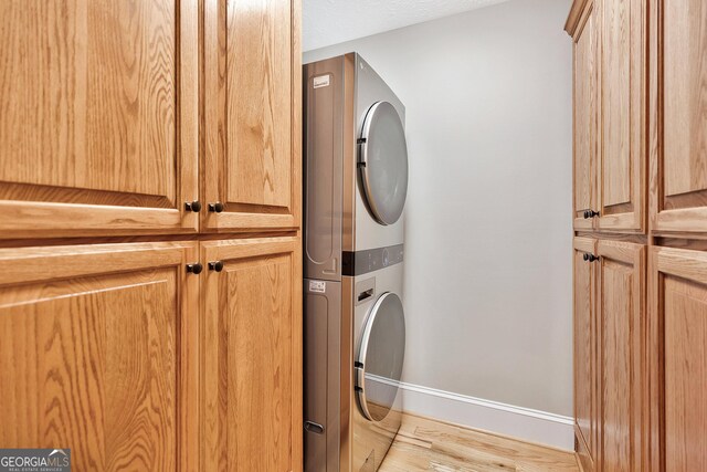 201 Hickory Hill Ln, Martin, GA 30557 - laundry area featuring cabinet space, stacked washer / dryer, light wood-style flooring, and baseboards