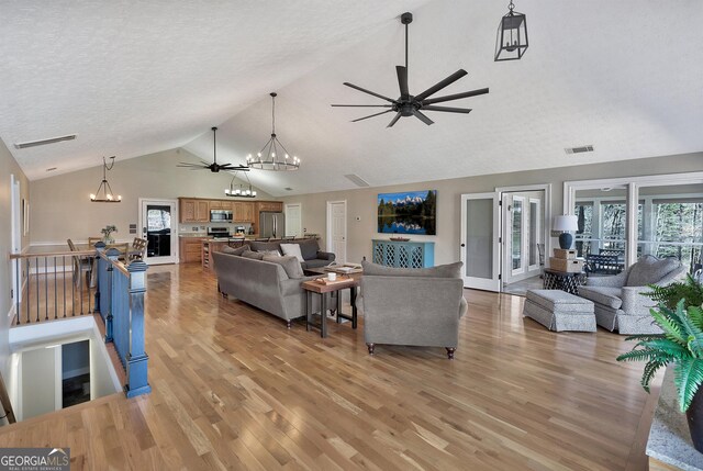 201 Hickory Hill Ln, Martin, GA 30557 - living room featuring a ceiling fan, a chandelier, light wood-style floors, high vaulted ceiling, and a textured ceiling