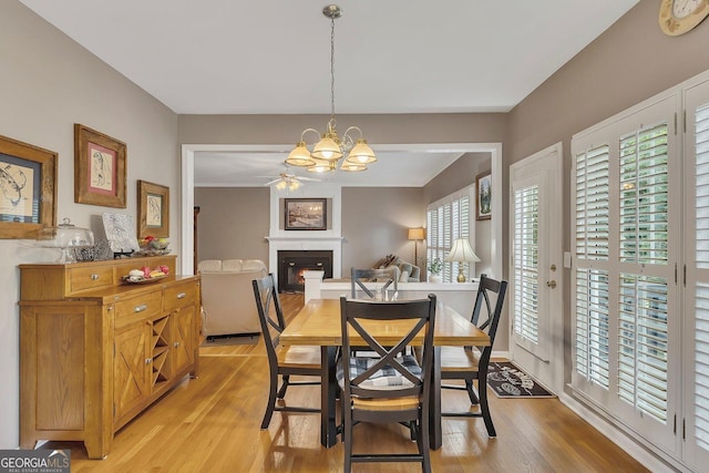 6302 Manassas Pass NW, Acworth, GA 30101 - dining area with a lit fireplace, light wood-type flooring, a chandelier, and a ceiling fan