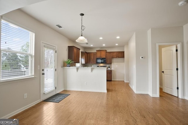 203 Creek View Ln, Acworth, GA 30102 - kitchen featuring black microwave, a peninsula, light wood-type flooring, a breakfast bar area, and pendant lighting