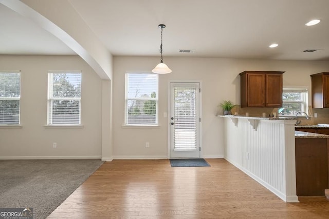 203 Creek View Ln, Acworth, GA 30102 - kitchen featuring light wood-type flooring, a breakfast bar, brown cabinets, pendant lighting, and recessed lighting