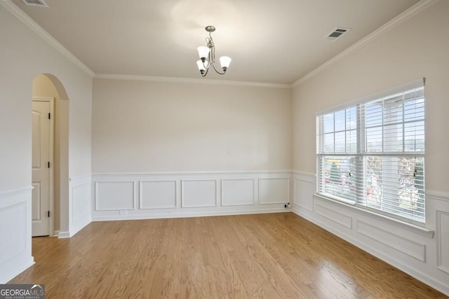 203 Creek View Ln, Acworth, GA 30102 - empty room featuring arched walkways, light wood finished floors, a chandelier, a wainscoted wall, and crown molding