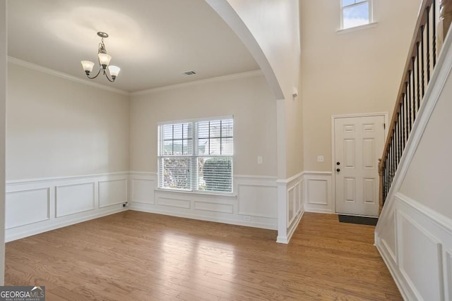 203 Creek View Ln, Acworth, GA 30102 - foyer entrance with a chandelier, light wood-style floors, a wainscoted wall, ornamental molding, and arched walkways